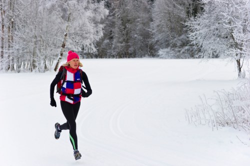 Women jogging through snowy forest.